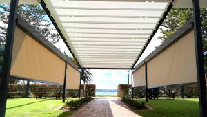 Two men sitting on the bench & talking with each other at the garden backyard of the restaurant and white color aluminum pergola roof system