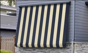 Grey & white lines folding awnings on the home's window and grey and brown color wooden gate beside a window