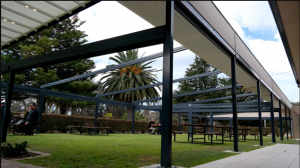 A man sitting on the bench at the garden cafe and white folding roof outside the garden café