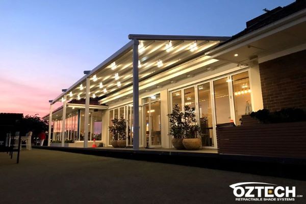 Luxurious home with multiple lights bulbs in the evening view, with an oztech logo in white at the bottom.